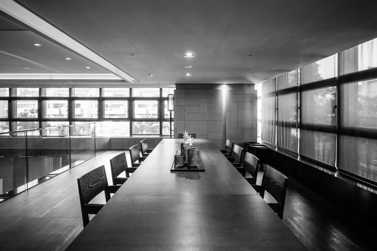 A long boardroom table in a darkened modern meeting room
