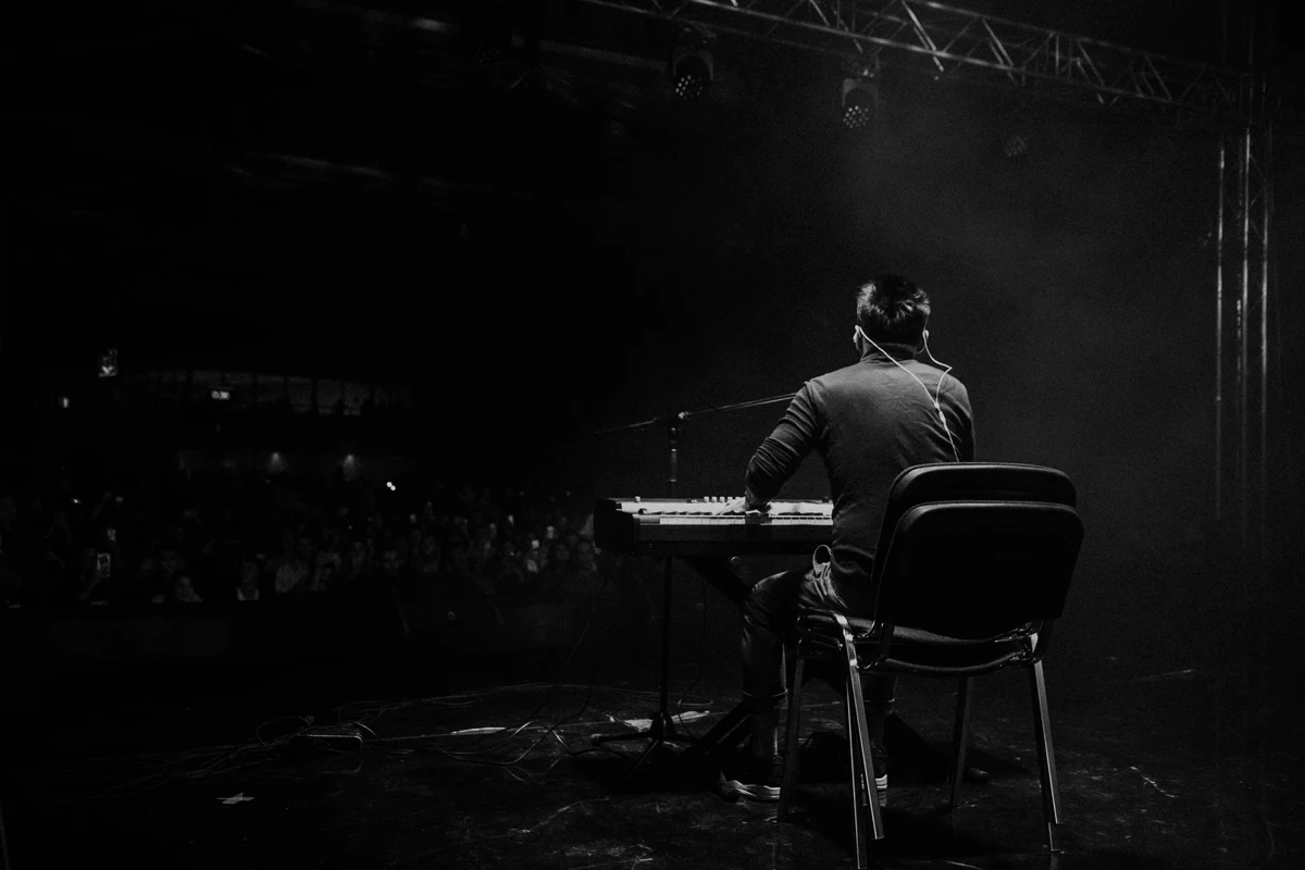 A live concert performance lit by stage lighting above a packed crowd.