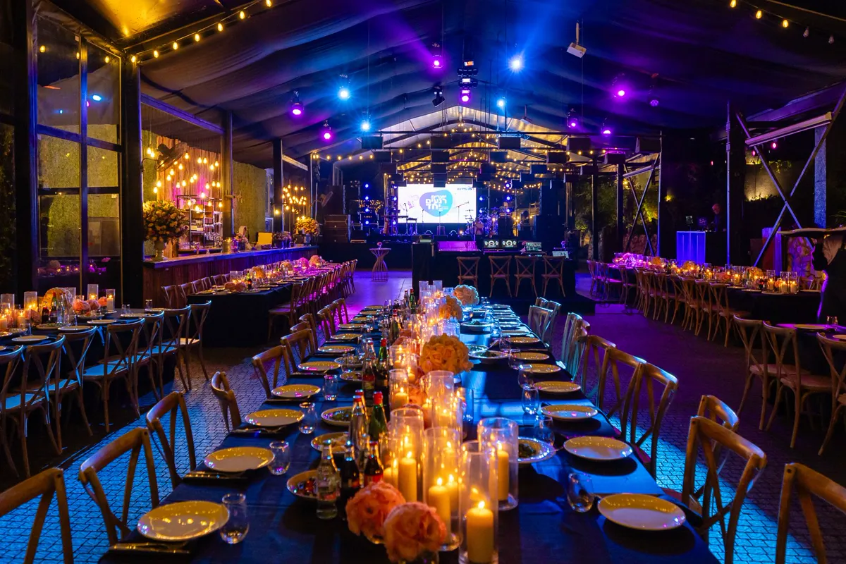 A candlelit gala dinner table set with crystal glassware and florals.