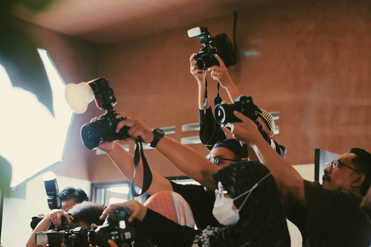 Photographers shooting arrivals along a red carpet.