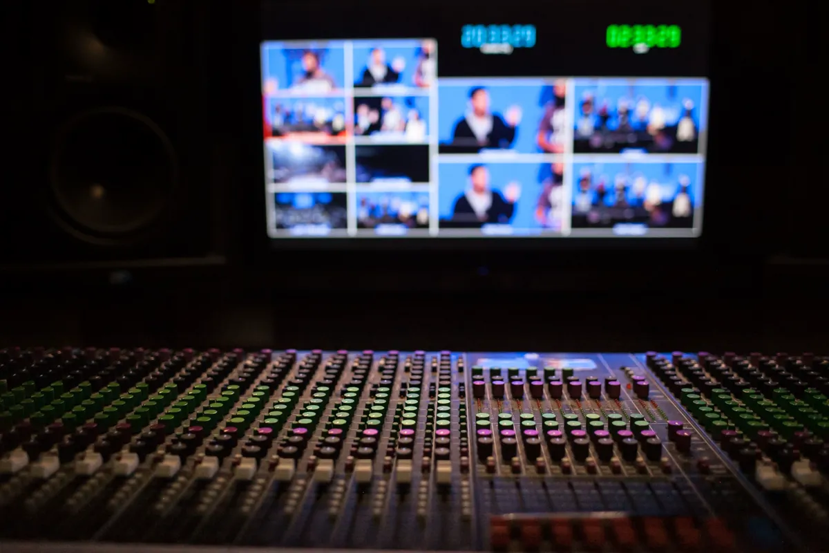Journalist at a modern newsroom broadcast desk surrounded by screens