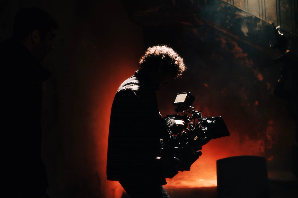 Cinema camera and crew working under production lighting on a film set