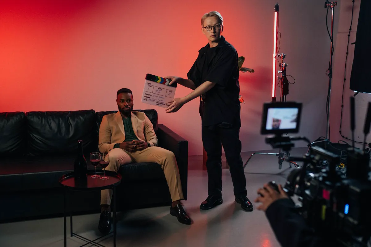 A crew member holding a clapperboard in front of an actor on a red-lit set.